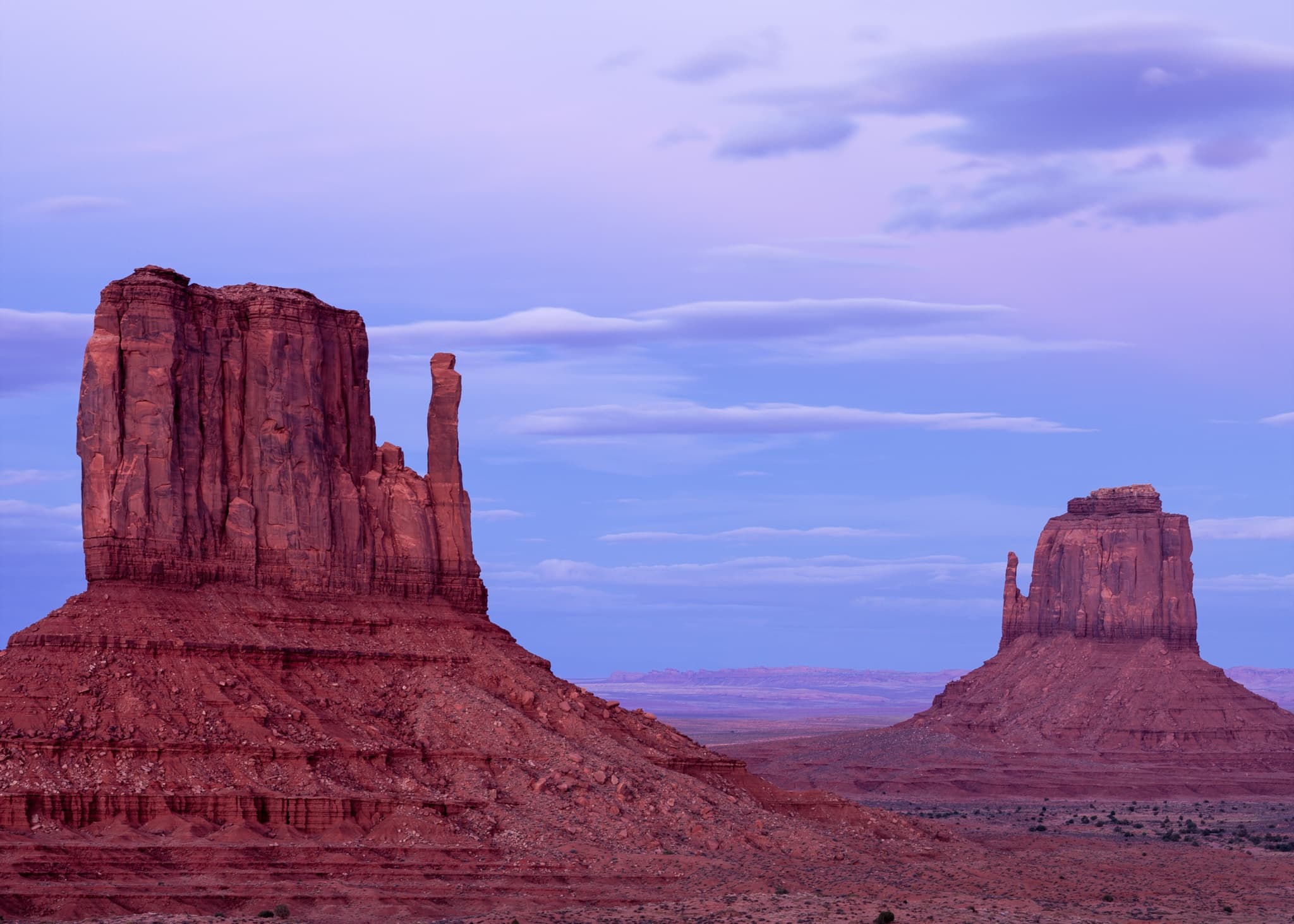 The East and West Mittens and Merrick Butte at blue hour in Monument Valley, the sandstone formations holding their deep red while the sky transitions through pink and blue, Arizona. Photograph by Marty Quinn