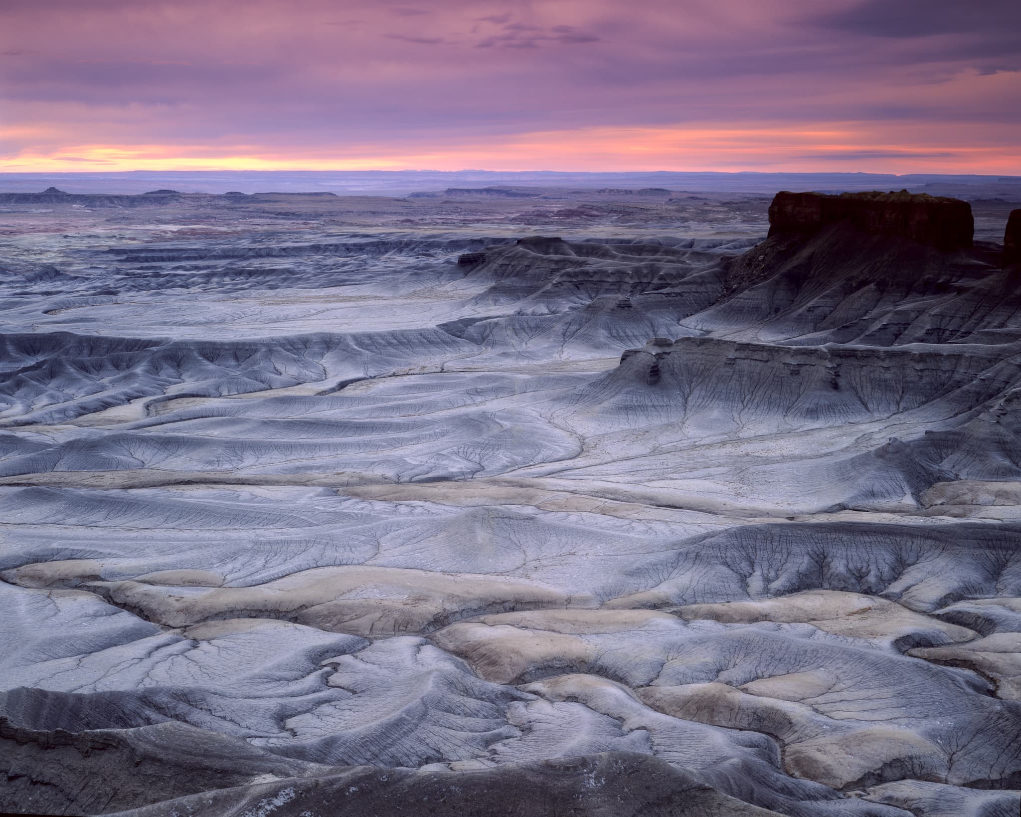 Sunrise over an exposed high-desert plateau that reads as lunar — pale, stripped to rock and sky, Utah. Photograph by Marty Quinn