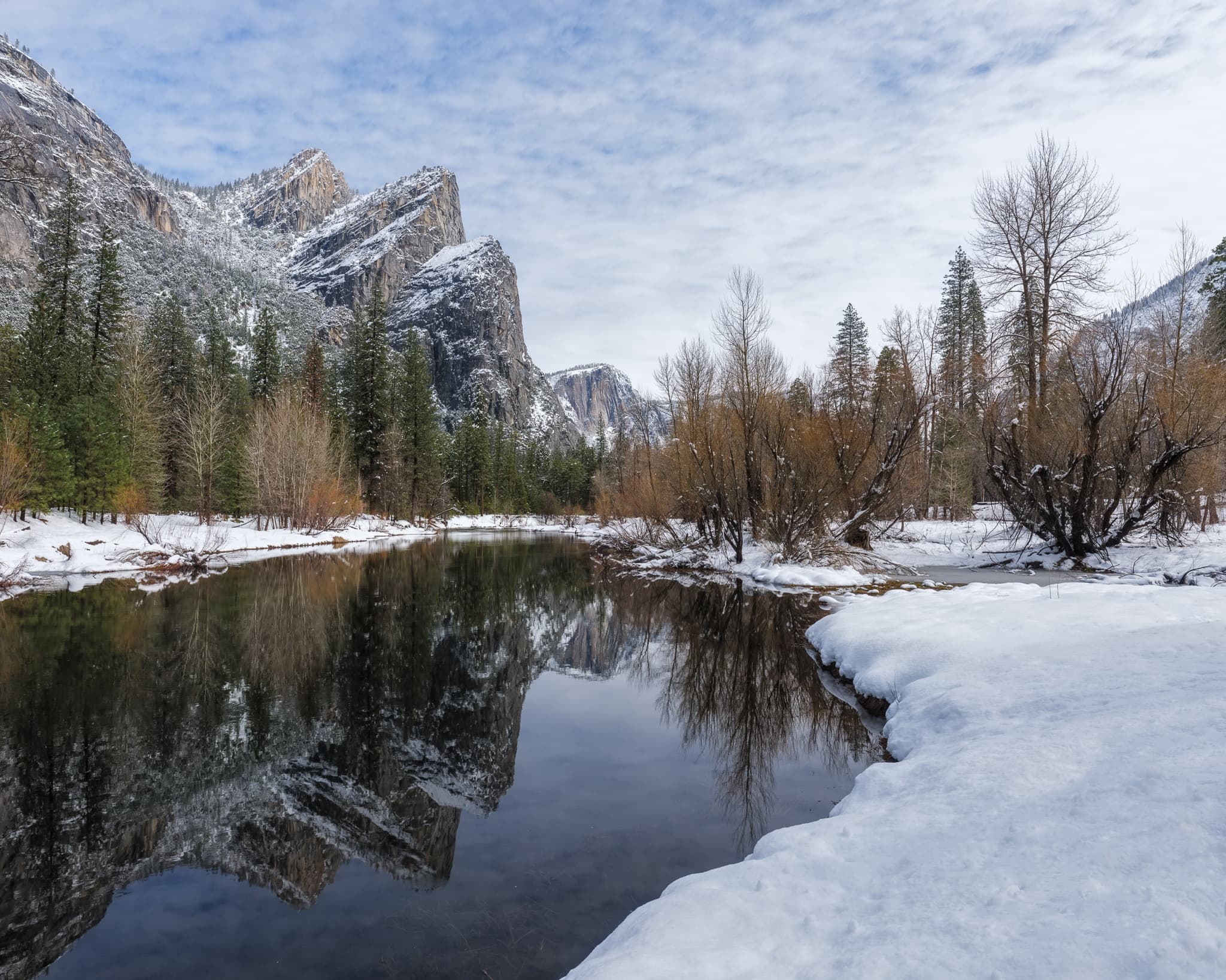 The Three Brothers — Eagle Peak, Middle Brother, Lower Brother — reflected in a calm section of the Merced River in Yosemite Valley after a winter snowstorm, California. Photograph by Marty Quinn